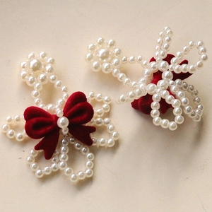 Close-up of pearl flower hair clips with red velvet bows and elegant beaded details