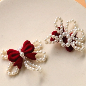 Close-up of vintage dark red flocked bow hair clips with white pearl flower embellishments