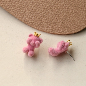 Macro view of pink flocked teddy bear earrings with golden crown and pin details