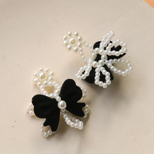 Detail of velvet bow hair clips with white pearls in flower pattern on metallic clip