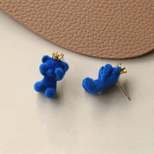 Detail view of blue flocked crown bear earring with silver needle on leather prop