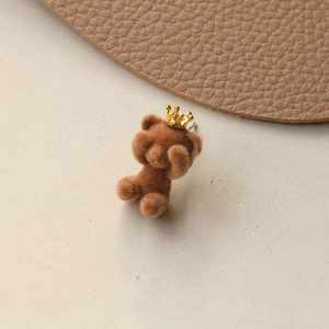 Macro view of brown flocked crown bear charm with detailed fuzzy texture and golden accents