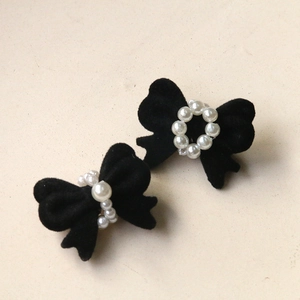 Detail of elegant black velvet bow hair clips featuring a center faux pearl ring decoration