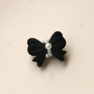 Detail of a black flocked bow with elegant white pearl center for DIY jewelry making