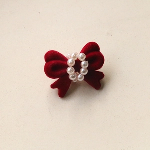 Detail of red flocked bow hair accessory with central faux pearl embellishment