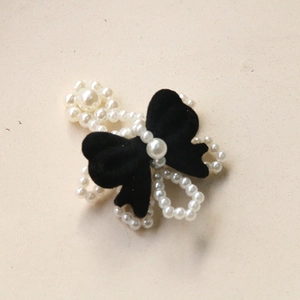Detail of a black velvet bow with white pearls for elegant DIY jewelry crafting