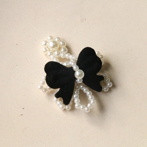 Detail view of a black velvet bow and elegant white pearl flower for DIY hair accessories