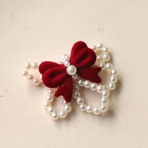 Macro view of red velvet bow with white faux pearl beads for jewelry DIY accessories