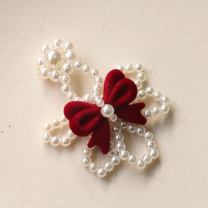 Detail of beaded pearl flower ornament with a deep red velvet bow for DIY accessories