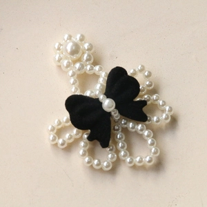 Macro shot of handmade hair clip featuring white imitation pearls and black velvet bow