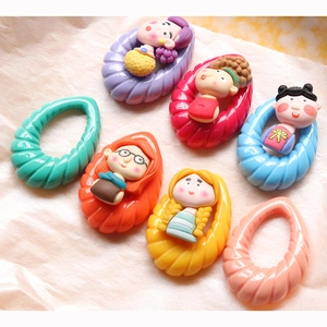 Dettaglio macro di ciondoli a spirale in acrilico con mini figurine di ragazze in argilla