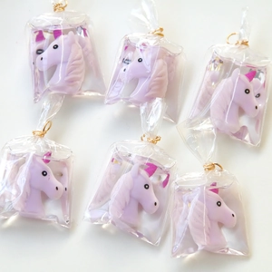 Close-up of DIY unicorn resin charms in transparent bags with gold metal hooks