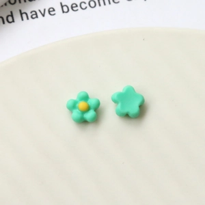 Macro view of mint green acrylic flower charms with yellow center on white ceramic plate