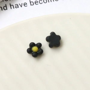 Detailed macro view of black matte floral resin charms with bright yellow centers