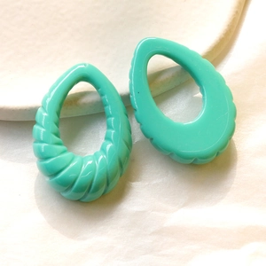 Dettaglio macro di ciondoli in resina a spirale verde menta per creazione di gioielli