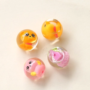 Gros plan de quatre perles en résine transparente avec animaux et fruits mignons