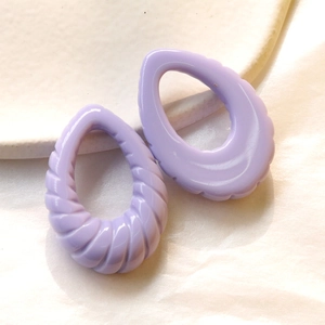 Dettaglio dei ciondoli a goccia in acrilico lavanda con trama a spirale per gioielli
