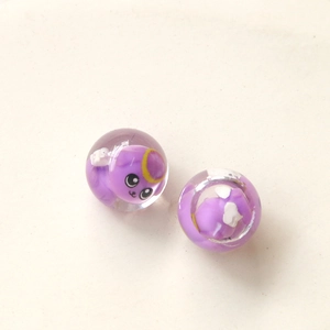 Détail de deux perles en résine violette transparente avec des motifs d'animaux mignons