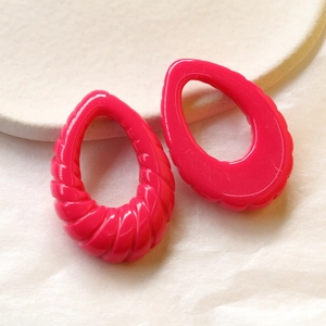 Dettaglio macro di ciondoli a goccia a spirale magenta con finitura in resina lucida