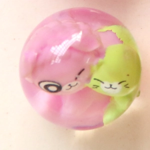Détail macro de breloques en résine transparente avec des figurines d'animaux en rose et vert