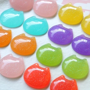 Close-up of glitter cat-shaped resin charms in various colors for DIY crafts