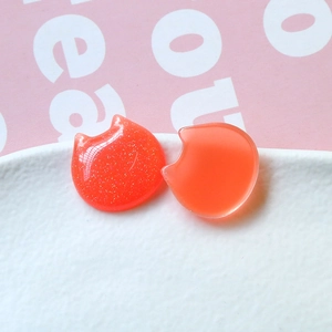 Close-up of glitter resin cat charms in bright orange and translucent pink for DIY crafts