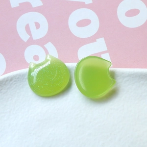 Macro detail of cat-shaped resin cabochons in green glitter and translucent finishes