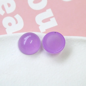 Gros plan d'accessoires demi-sphères en résine violette pailletée et éclats dorés