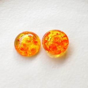 Dettaglio di cabochon in resina ambrata con scaglie di alluminio interne brillanti