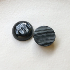 Dettaglio di cabochon in resina a righe grigio scuro con lati bombati e piatti levigati