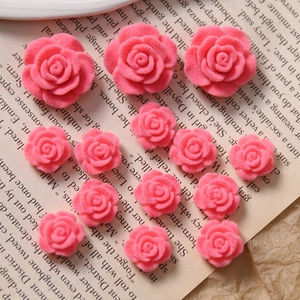 Macro shot of pink flocked acrylic rose charms for DIY jewelry on vintage paper