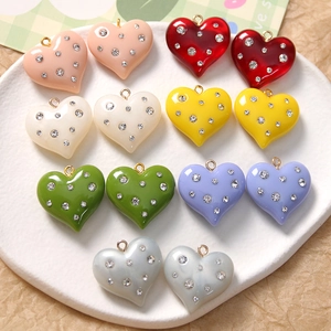 Macro detail of heart-shaped resin charms with inlaid rhinestones and gold loops