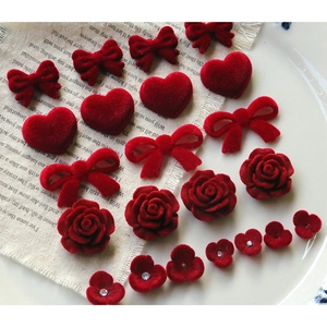 Macro detail of red velvet heart, bow, and rose charms for DIY jewelry making