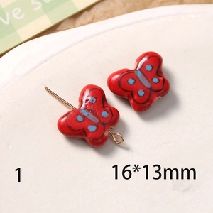 Vue macro d'un charme papillon en céramique peint à la main 16x13mm avec épingle dorée