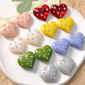 Macro shot of colorful resin heart charms with rhinestones and golden metal loops