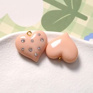 Detail of peach resin heart charms with rhinestones and gold loops for DIY jewelry