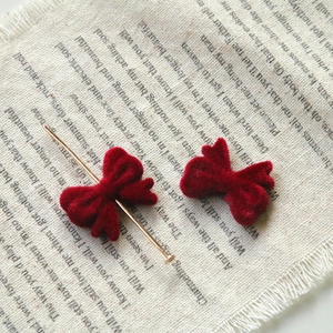 Macro shot of red velvet ribbon bow on a gold metal pin for DIY hair accessories