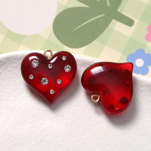 Detail of red heart-shaped resin charms with rhinestones and gold hanging rings