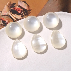 Detalle de perlas blancas iridiscentes redondas y de gota en plato cerámico para joyería DIY