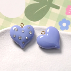 Macro detail of lavender resin heart charms with rhinestones and gold metal ring loops