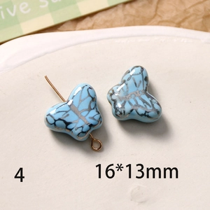Détail d'une perle papillon en céramique bleu clair 16x13mm avec texture dorée
