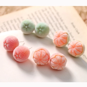 Cute 3D flocked orange stud earrings on open book pages for a warm winter fashion style