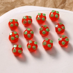 Detailansicht glänzend roter Glas-Persimone-Perlen mit grünen Blättern für DIY-Schmuck