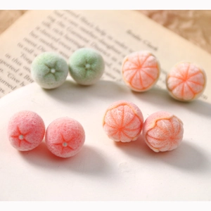 Macro detail of flocked orange and fruit shaped earring components with soft texture