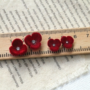 Detailed comparison of red velvet flower earrings with rhinestones against a wooden ruler