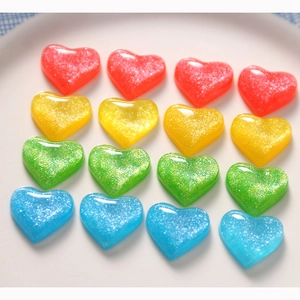 Flat lay of 16 heart resin DIY accessories in four colors with sparkling glitter finish