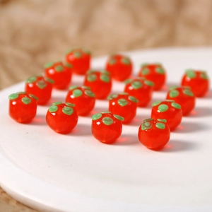 Detail von leuchtend orangen Persimone-Glasperlen für DIY-Schmuck mit grünen Blattakzenten