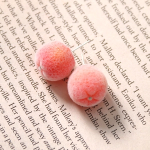 Close-up of pink gradient flocked peach earrings on a vintage literary book background