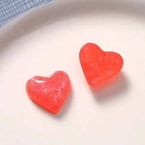 Close-up of heart-shaped red resin charms with fine silver glitter for DIY jewelry crafts