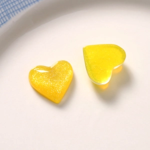Macro shot of two yellow heart resin glitter charms for DIY jewelry and hair accessories